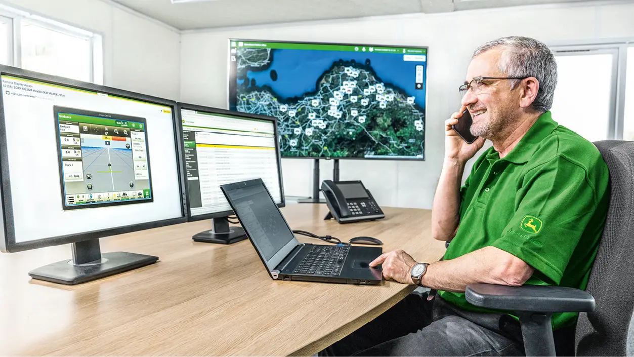 Mann telefoniert im Büro, Bildschirme
