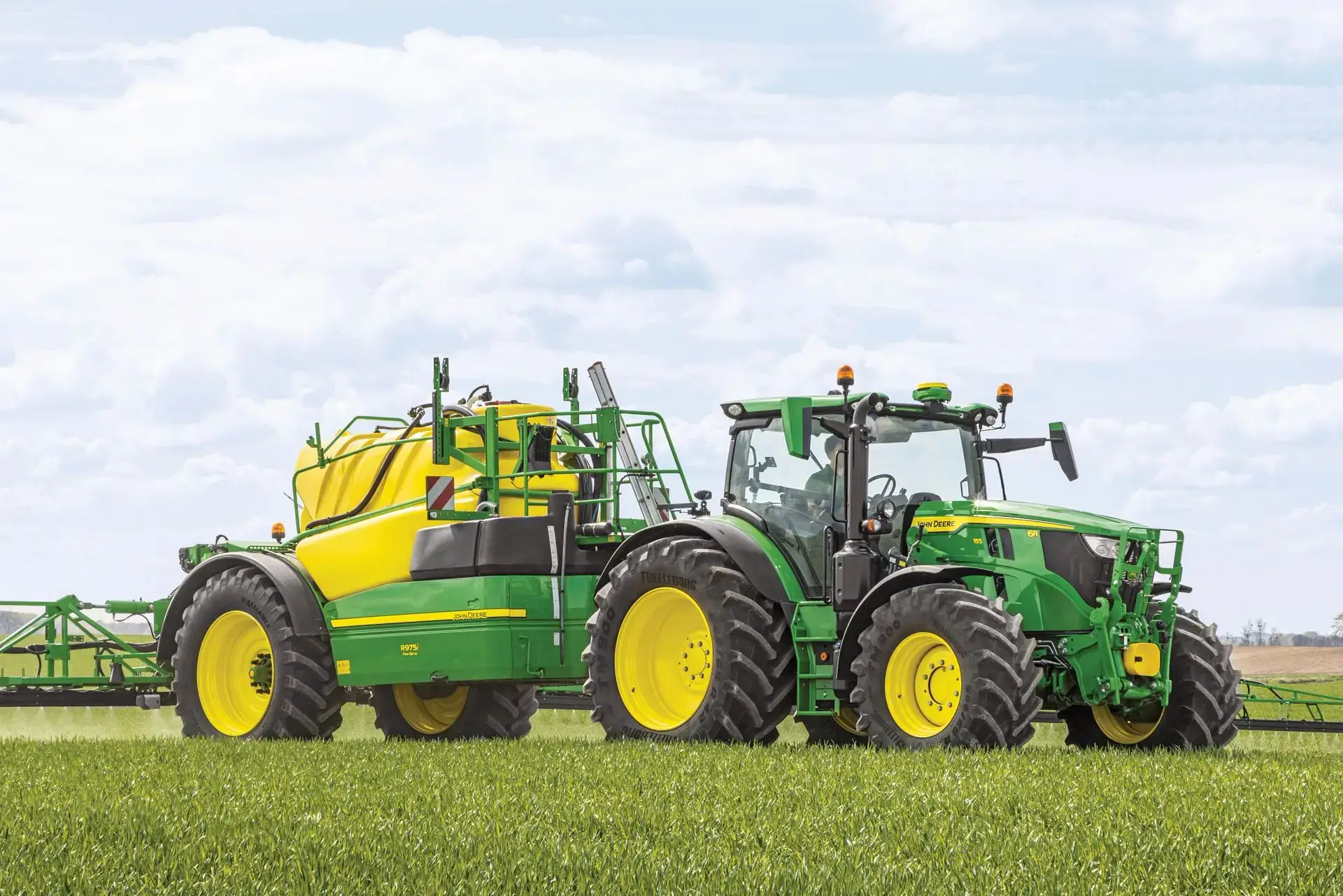 John Deere Traktor und Dungstreuer auf dem Feld
